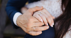 couple holding hands showing wedding rings